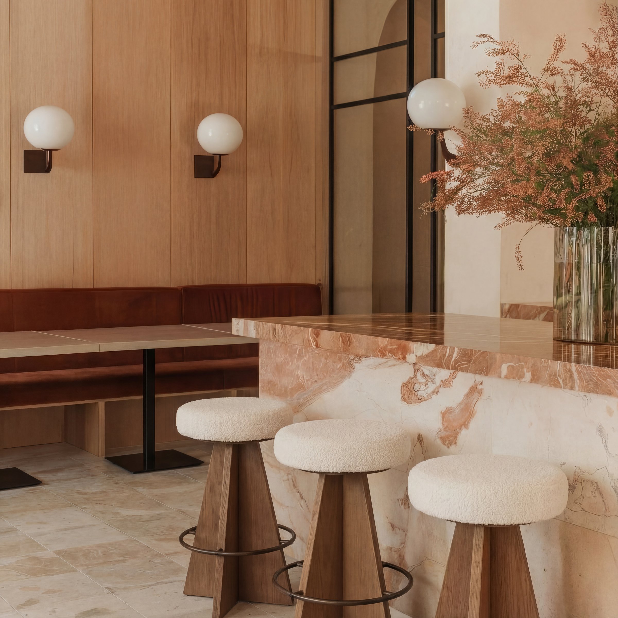 Marble counter with bouclé bar stools and brass wall sconces — residential specification by Ademchic