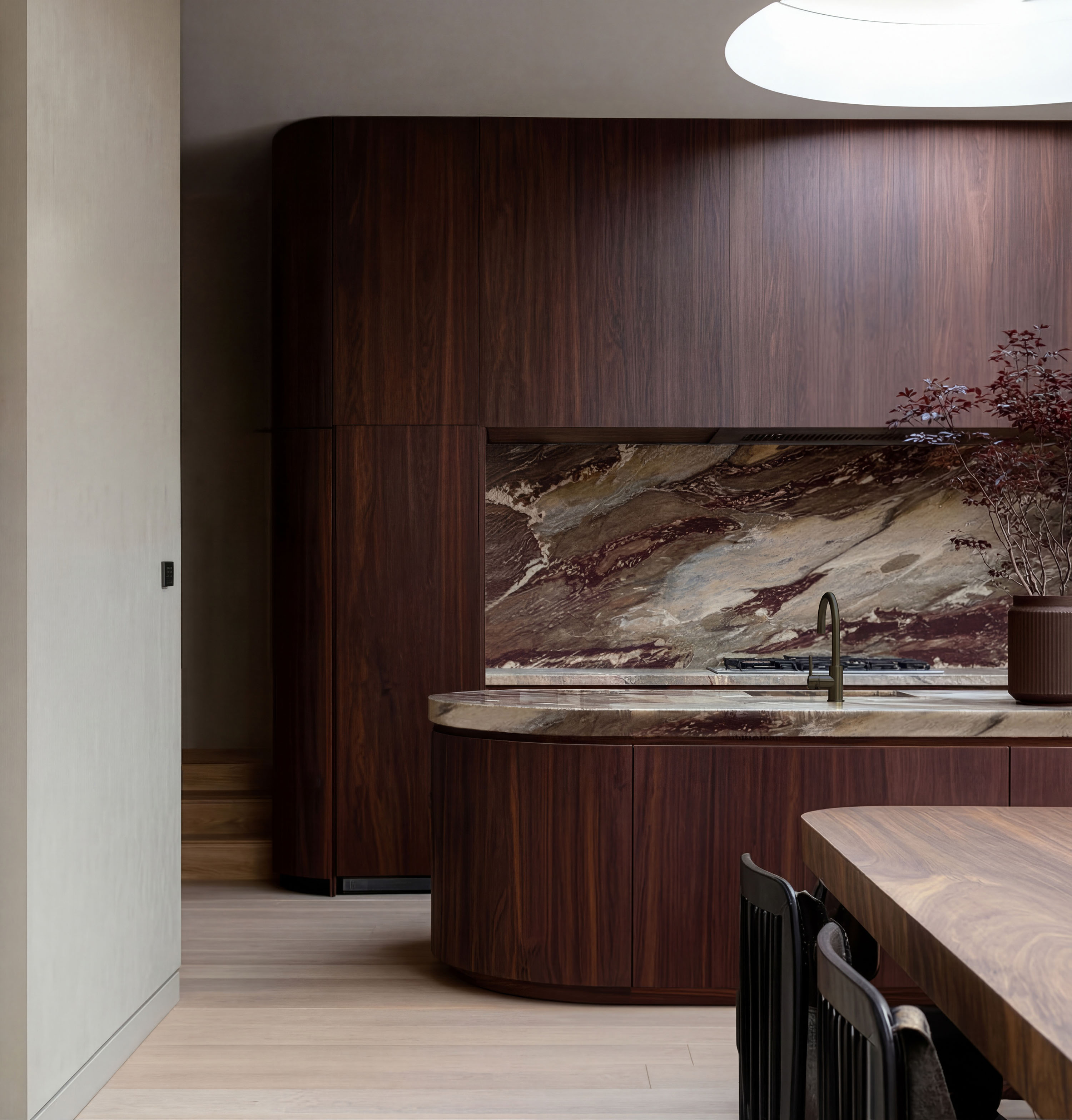 Bespoke dark walnut kitchen with curved island, marble splashback and brass detailing