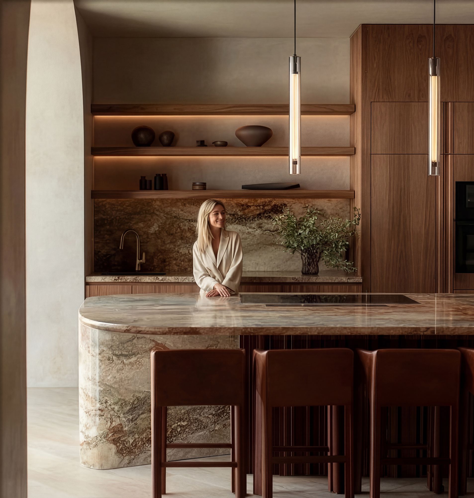 Luxury kitchen with curved marble island, walnut cabinetry, pendant lighting and open shelving