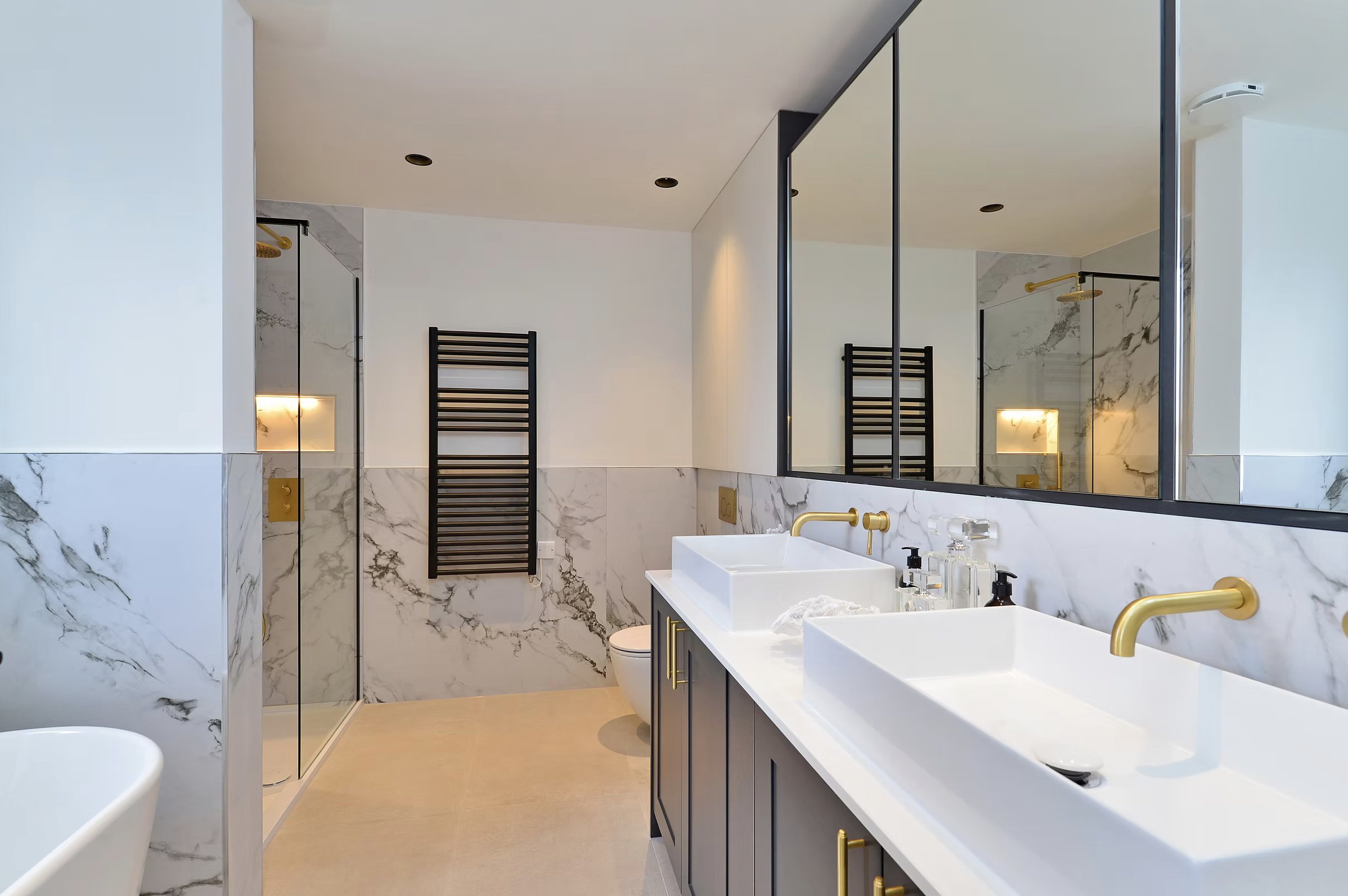Alfold Gardens completed primary bathroom with marble, dual basins and gold fixtures — specification by Ademchic
