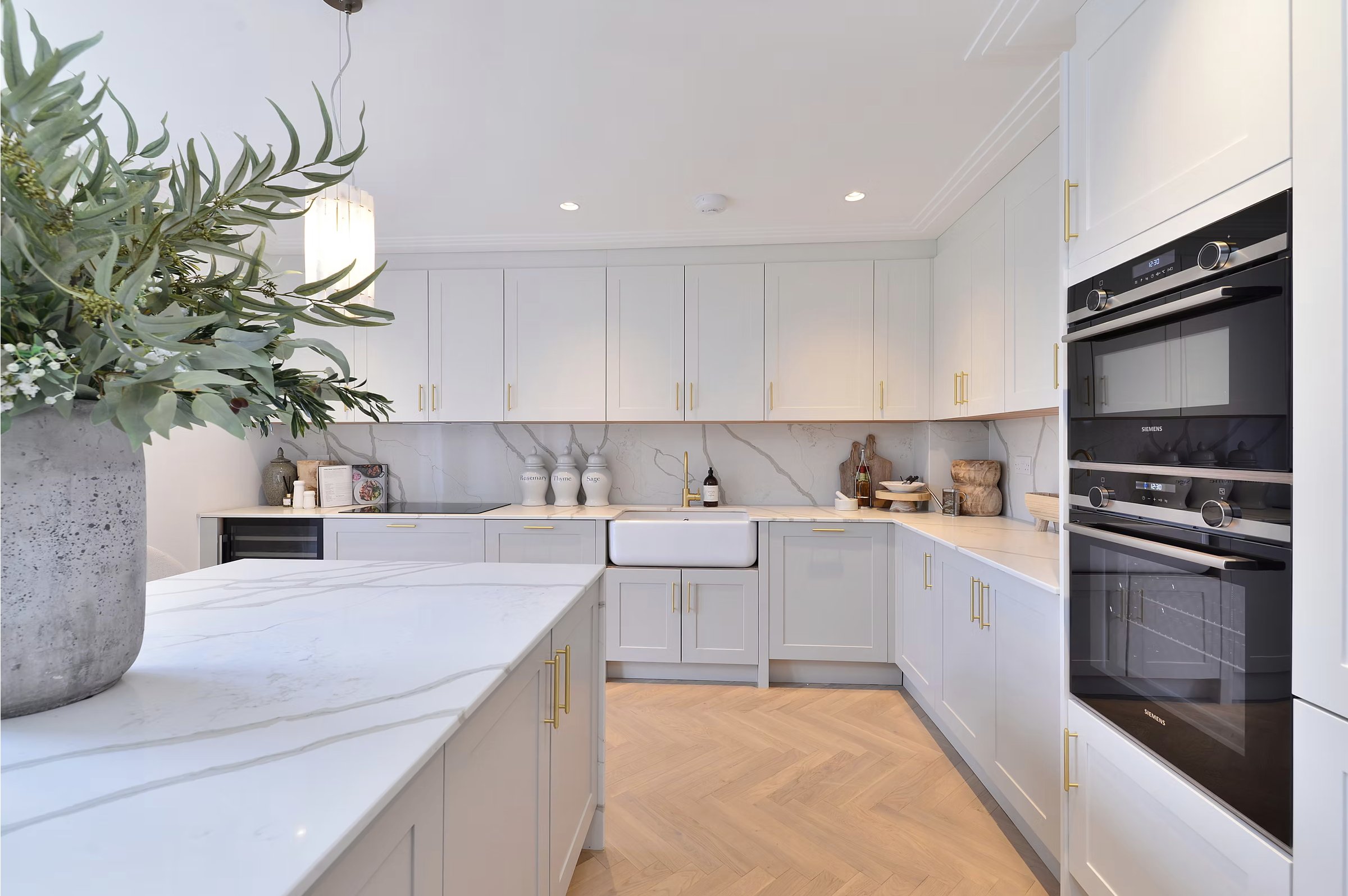 Alfold Gardens completed kitchen with marble countertops, island layout and gold hardware — interior design by Ademchic