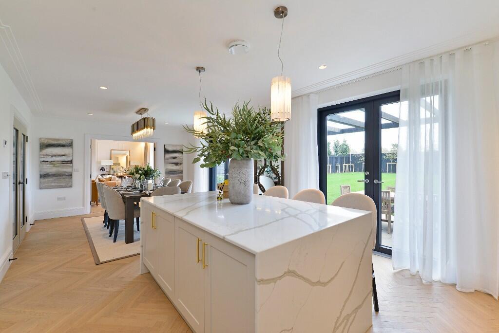 Alfold Gardens completed kitchen and dining area with marble island, gold hardware and garden views — by Ademchic