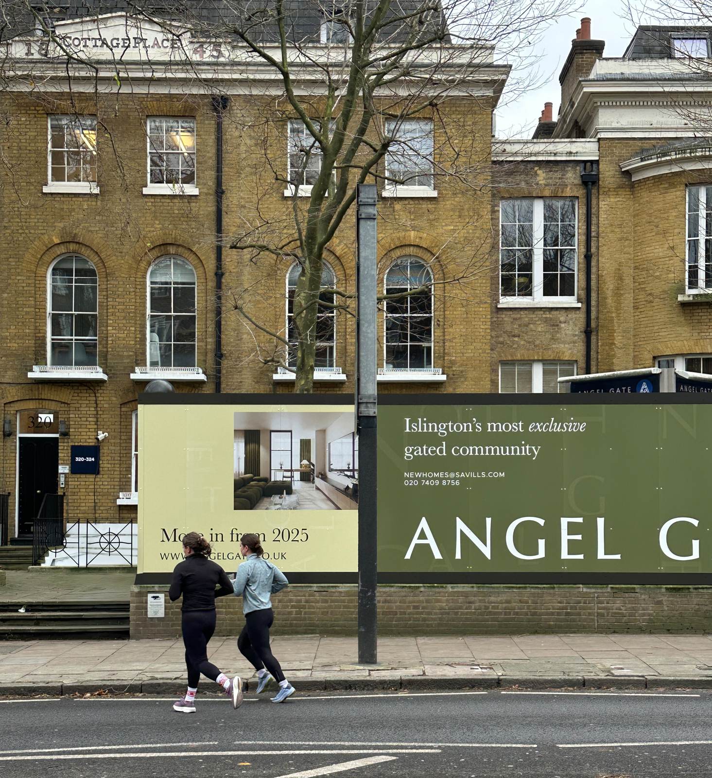 Angel Village site hoarding on City Road, Islington showing apartment interiors and development branding